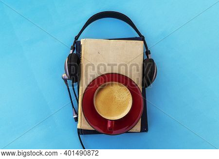 Audio Book Concept. Black Headphones With Books And Cup Of Fresh Coffee On Blue Background. Top View