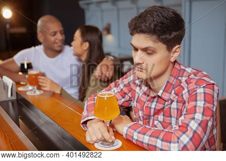 Young Depressed Man Feeling Lonely, Drinking Alone At The Bar, Affectionate Couple Cuddling On Backg