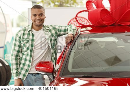 Horizontal Portrait Of A Happy African Man Smiling To The Camera Leaning On His New Automobile At Th