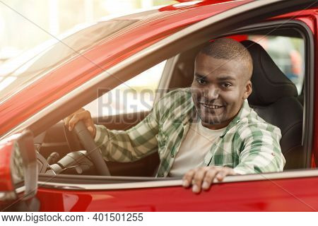 Happy African Man Smiling To The Camera While Getting In A New Car At The Dealership. Cheerful Male 