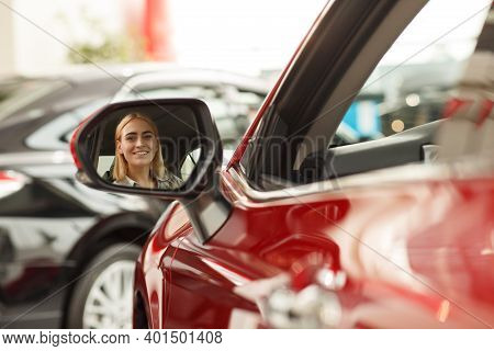 Gorgeous Cheerful Young Woman Smiling To The Camera Through Side Mirror Of Her New Automobile. Attra