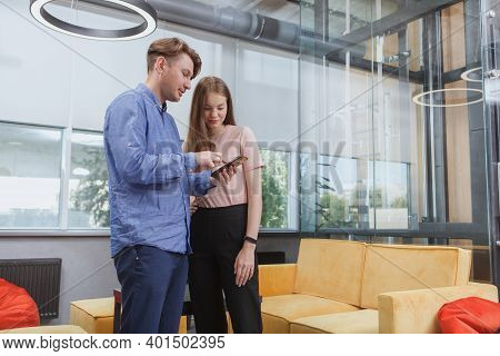 Low Angle Shot Of Two Colleagues Using Smart Phone At The Office, Copy Space