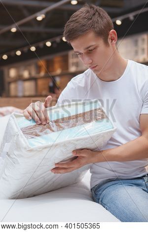 Vertical Shot Of A Young Man Choosing Orthopeic Mattress To Buy