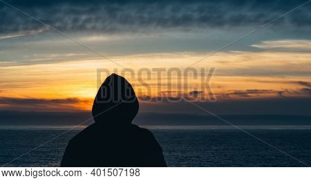The Picture Shows A Portrait Of The Silhouette Of A Young Man In A Hooded Sweatshirt Facing The Sea 