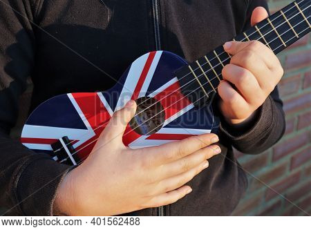 Ukelele With Union Flag Being Played By Child. Close Up Of Hands.