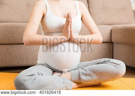 Beautiful Young Pregnant Woman Sitting On Mat In Yoga Pose At The Home. Pregnancy Yoga And Fitness C