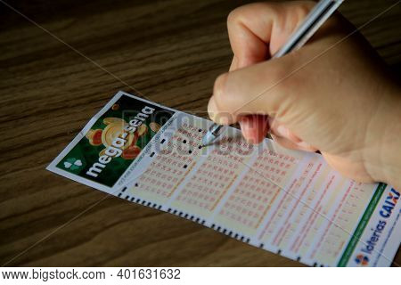 Salvador, Bahia, Brazil - January 2, 2021: Person Scoring Mega Sena Lottery Ticket In The City Of Sa