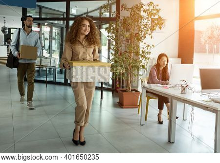 Young business people of mixed-races with boxes come back to office. Colleagues going to work in modern workspace, teamwork together.