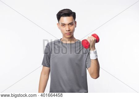 Young Handsome Asian Man In Sport Outfits Exercising With Dumbbell And Looking To Camera Isolated On