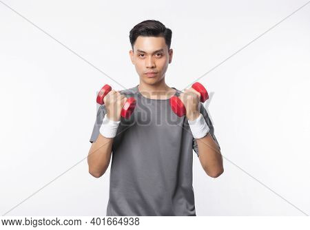 Young Handsome Asian Man In Sport Outfits Exercising With Dumbbells And Looking To Camera Isolated O
