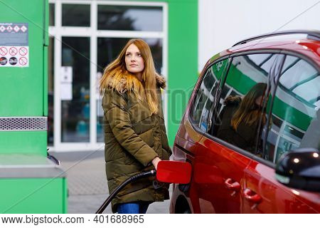 Young Caucasian Woman At Self-service Gas Station, Hold Fuel Nozzle And Refuel The Car With Petrol, 