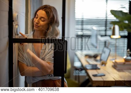 Young Woman Controlling Room Temperature With A Smart Thermostat At Home. Home Comfort And Smart Hea