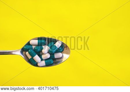 On A Yellow Background Banner, Pills In A Spoon. Place For Your Text. High Quality Photo