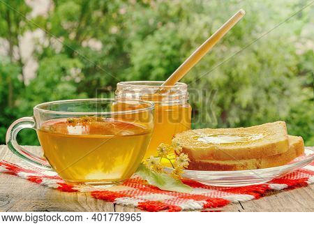 Jar Of Linden Honey, Cup Of Linden Tea And Linden Flowers On Wooden Table On A Sunny Day