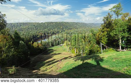 People Run Down The Side Of A Hill In The Gauja National Park On A Sunny Autumn Day. Long Shadows Fr