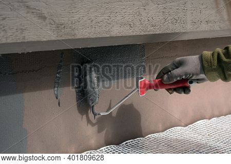 Man Painting Home Socle With Paint Roller. Close Up Of Rolling Grey Paint On Building Plinth. Home R