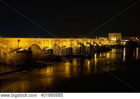 Cordoba, Spain - October 30, 2019: Illuminated Roman Bridge, Across Guadalquivir River With Torre De
