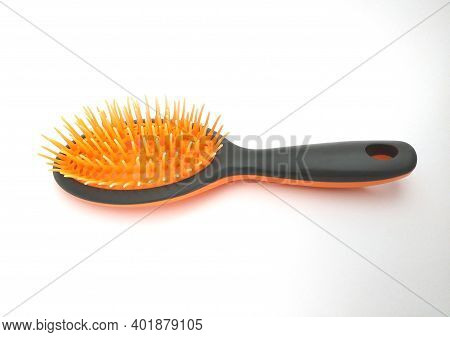 View Of Black Plastic Hairbrush With Orange Bristles Isolated On White Background. Black Rubber Mass