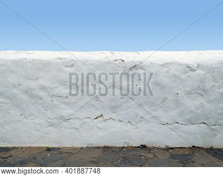 Close Up Of Rough White Wall Under Clear Blue Sky. Decorative White Brick Fence Wall Against Blue Sk