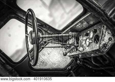 The Instrument Panel And Steering Wheel Of The Old Rusty Abandoned Tractor. Black And White Photo.