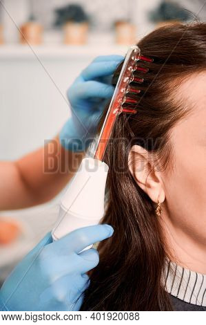 Close Up Of Doctor Trichologist Hand In Sterile Gloves Brushing Female Client Hair With Laser Hair G