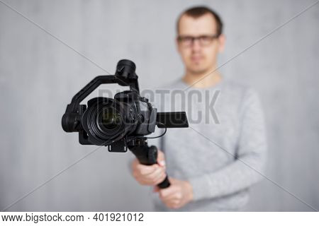 Close Up Of Modern Dslr Camera On 3-axis Gimbal Stabilizer In Videographer Hands Over Grey Backgroun