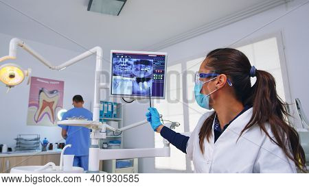 Dentistry Doctor Talking About Dental Surgery Showing X-ray On Monitor Unit, Patient Pov. Stomatolog