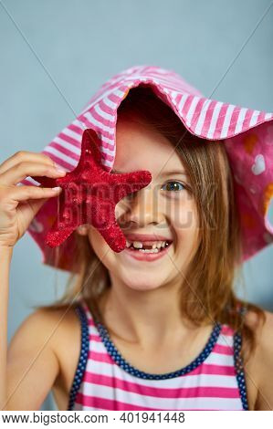 Smiling Little Girl Wearing Pink Hat Holding Starfish.