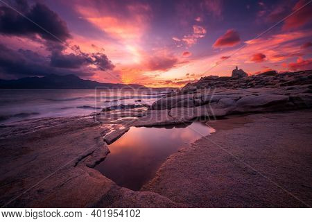 Beautiful Sunset Over An Ancient Genoese Tower On The Rocky Coastline Of At Punta Caldanu Near Lumio