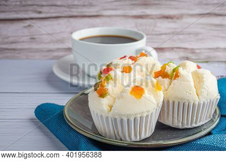 Side View Of Thai Steamed Cupcakes Topped With Dry Fruit On A Plate On A Blue Cloth With A White Cof