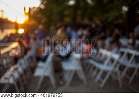 People Are Watching A Concert Of Classical Music. Blurred Young And Adult Women And Men And Other Pe