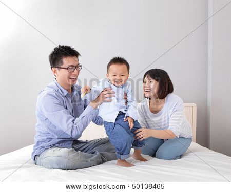 Happy Family Playing On White Bed