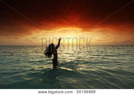 Vrolijke vrij jonge vrouw splashin in zee op zonsondergang