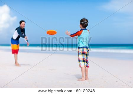 Father and son playing frisbee at beach