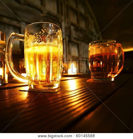 Mugs of beer in dark bar close-up