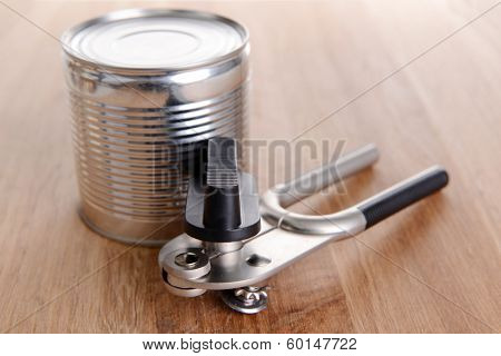 Can piercer with canned on wooden background