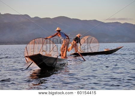 INLE LAKE, MYANMAR - DECEMBER 12, 2013: Fishermen at Inle Lake, Shan State, Myanmar  Intha people possess the leg-rowing style and the unique coop-like fishing equipment 