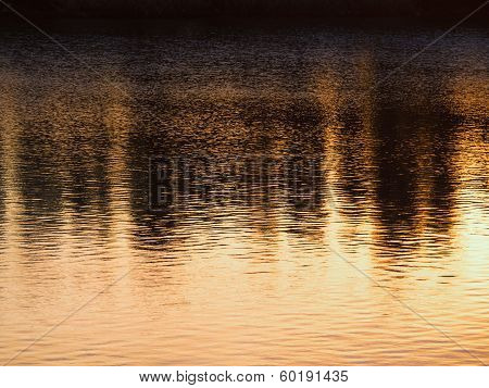 Black and gold sunset reflection on the river water