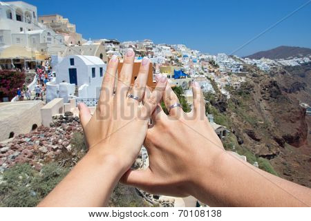 Honeymoon On Santorini Island - Hands With Wedding Rings Over Panorama Of Oia Village