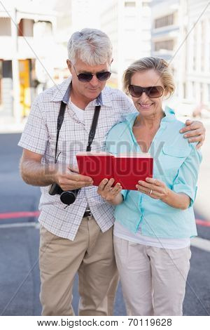 Happy tourist couple using tour guide book in the city on a sunny day