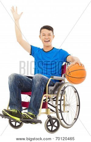 Young Man Sitting On A Wheelchair And Holding A Basketball