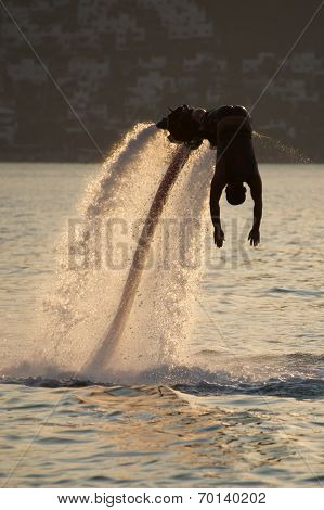 Flyboarder Silhouetted In Dive Towards Evening Sea