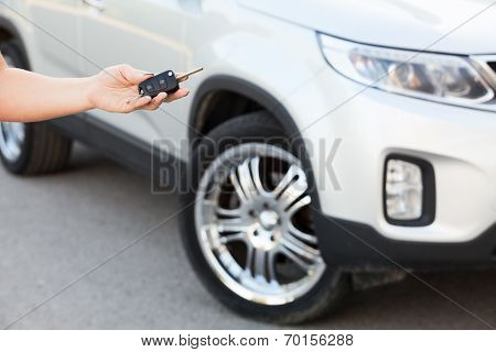 Female Hand Holding Car Key With Suv On Background
