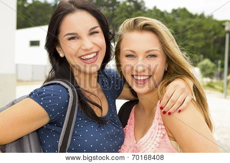 Two beautiful and happy teenage students lauthing 