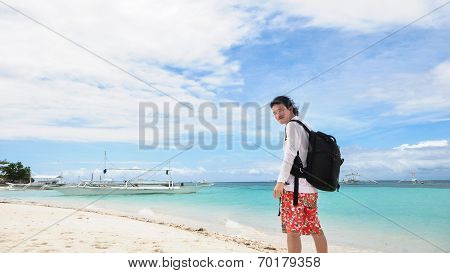 happy young man looking back at camera on tropical beach