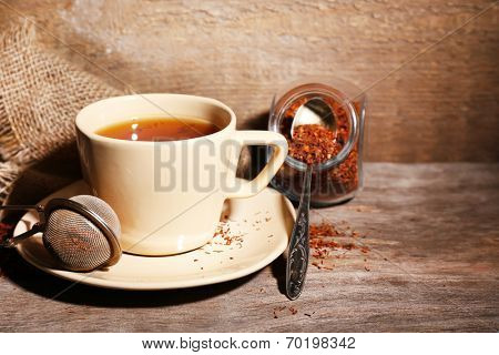Cup of tasty rooibos tea, on wooden table