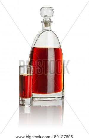 Carafe and high shot glass filled with brown liquid