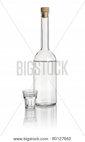 Liquor bottle and beveled shot glass filled with clear liquid
