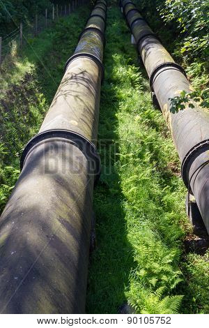 Two Large Black Water Pipes, Converging In Distance.