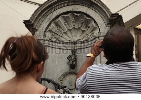 BRUSSELS, BELGIUM - AUGUST 13, 2012: Tourists look at the Manneken Pis in Brussels, Belgium.